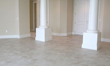 An empty room with a tiled floor, two columns, and a closed white door