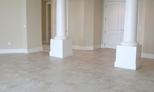 An empty room with a tiled floor, two columns, and a closed door